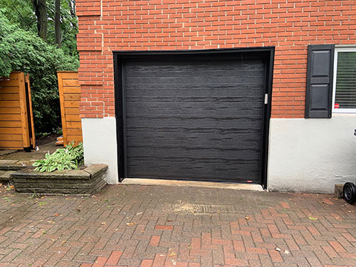 Maison en briques avec une porte de garage noire.