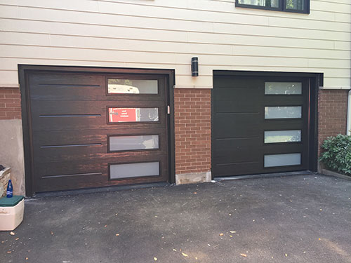 Deux portes de garage vitrées sur la façade d'une maison, ajoutant une touche moderne à l'architecture extérieure.