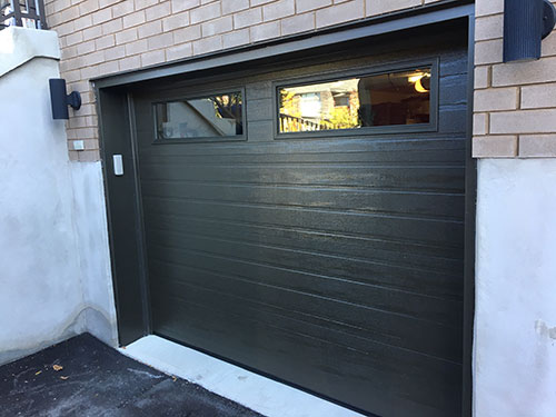 Porte de garage noire avec fenêtres, offrant un design moderne et élégant.