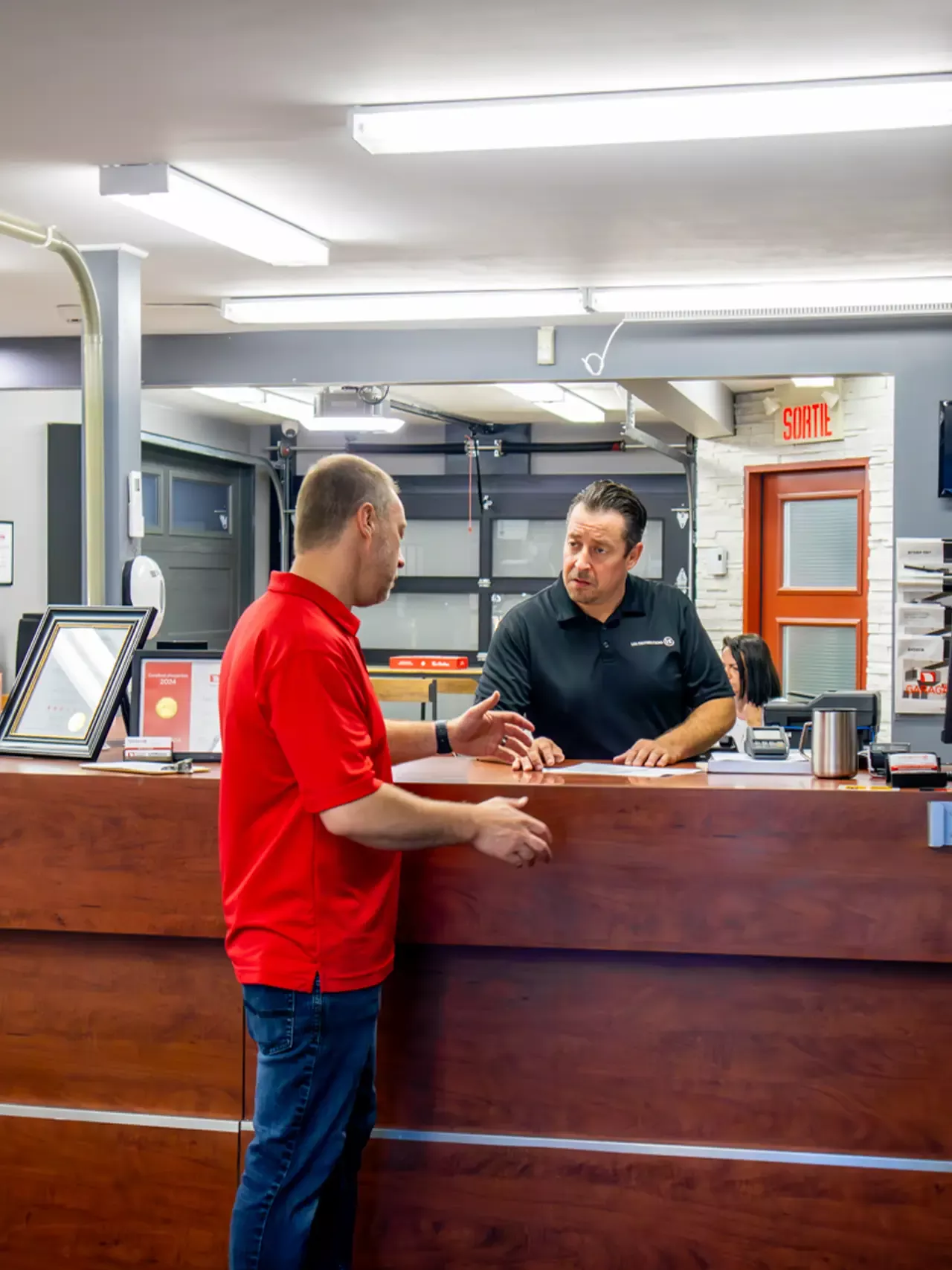 Deux hommes qui discutent ensemble au comptoir d'une entreprise de porte de garage Distribution BD