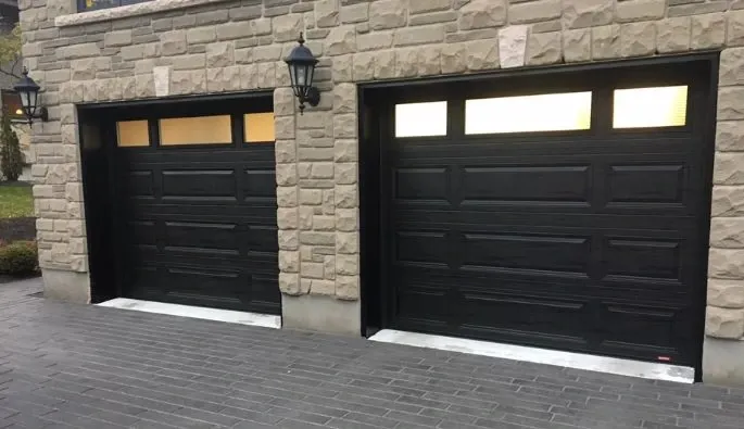 Deux portes de garage noires avec fenêtres, créant un look moderne et élégant